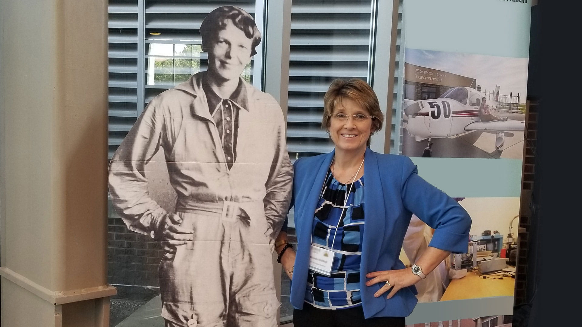 Ronda Walthall standing next to Amelia Earhart American aviator post board