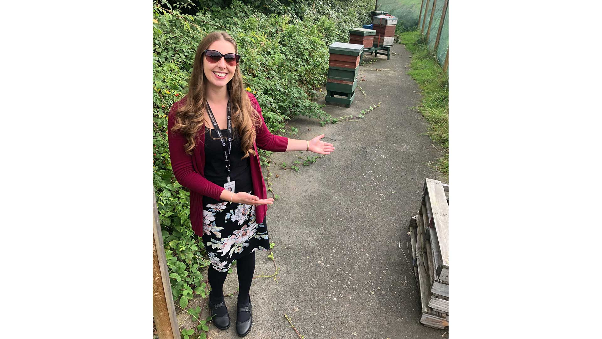 Fay Heywood, an advisor for the Collins Aerospace Environment, Health & Safety team in Wolverhampton, stands in front of the beehives she helped bring to the site.