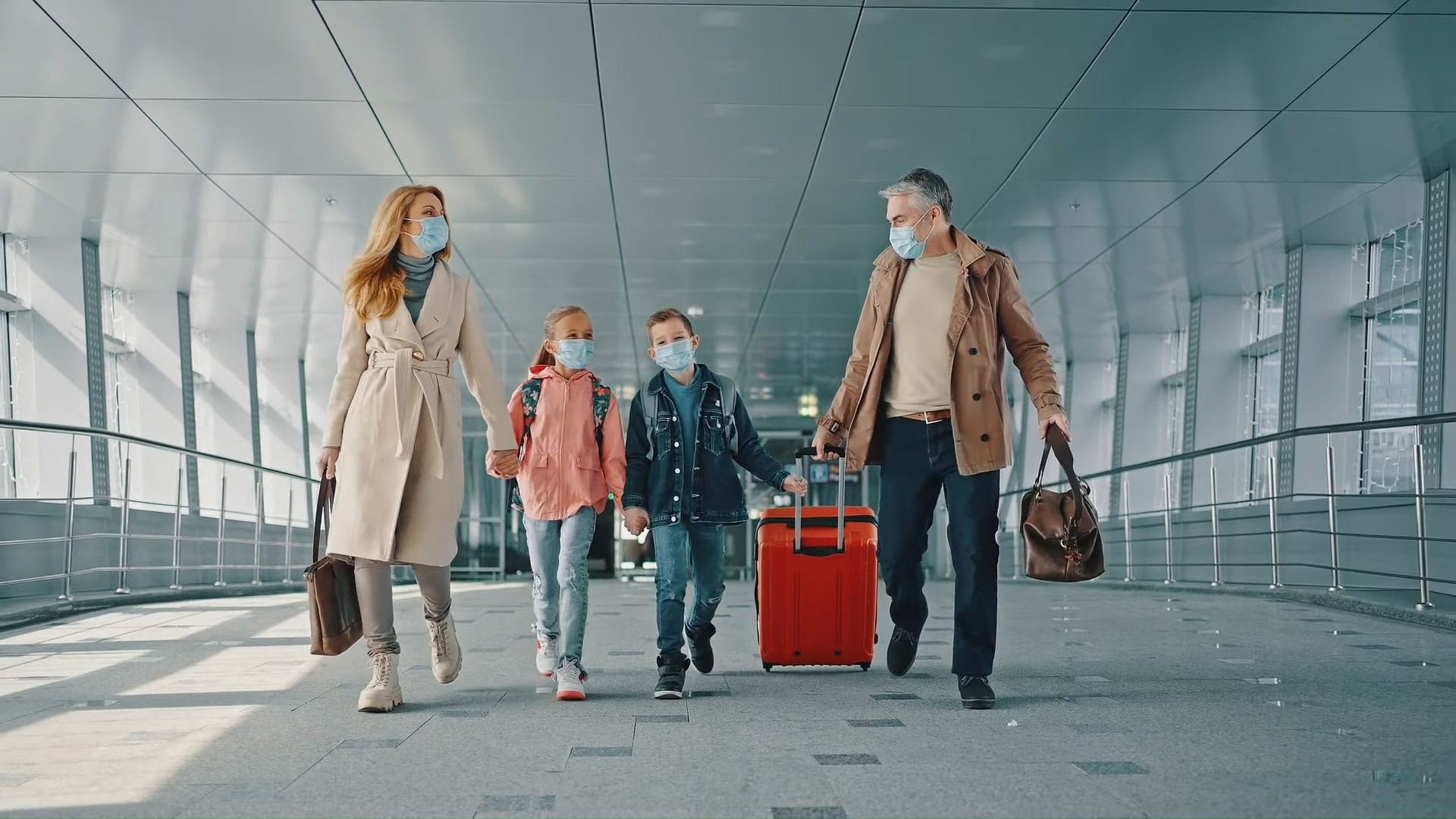 A mother and father with their two young children walk through an airport