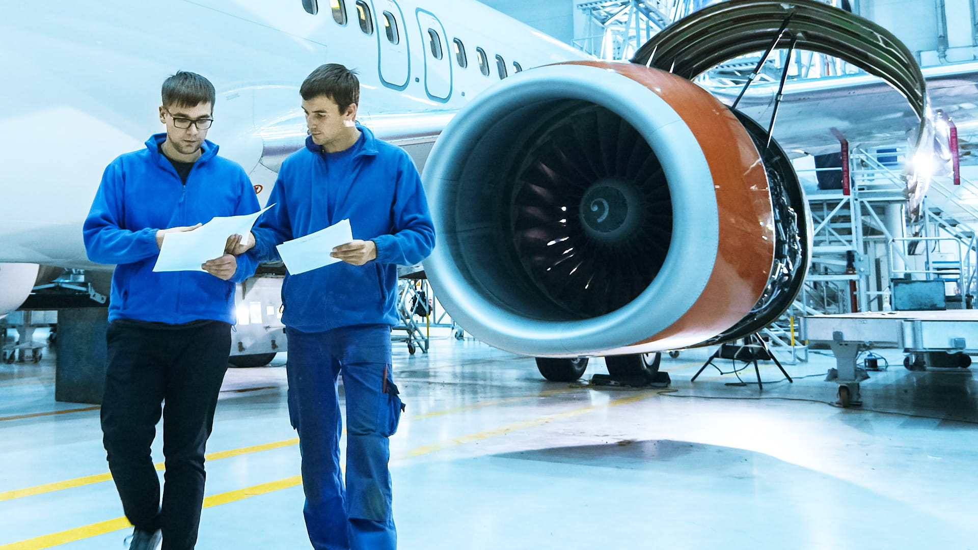 Two men walking in front of an airplane turbine