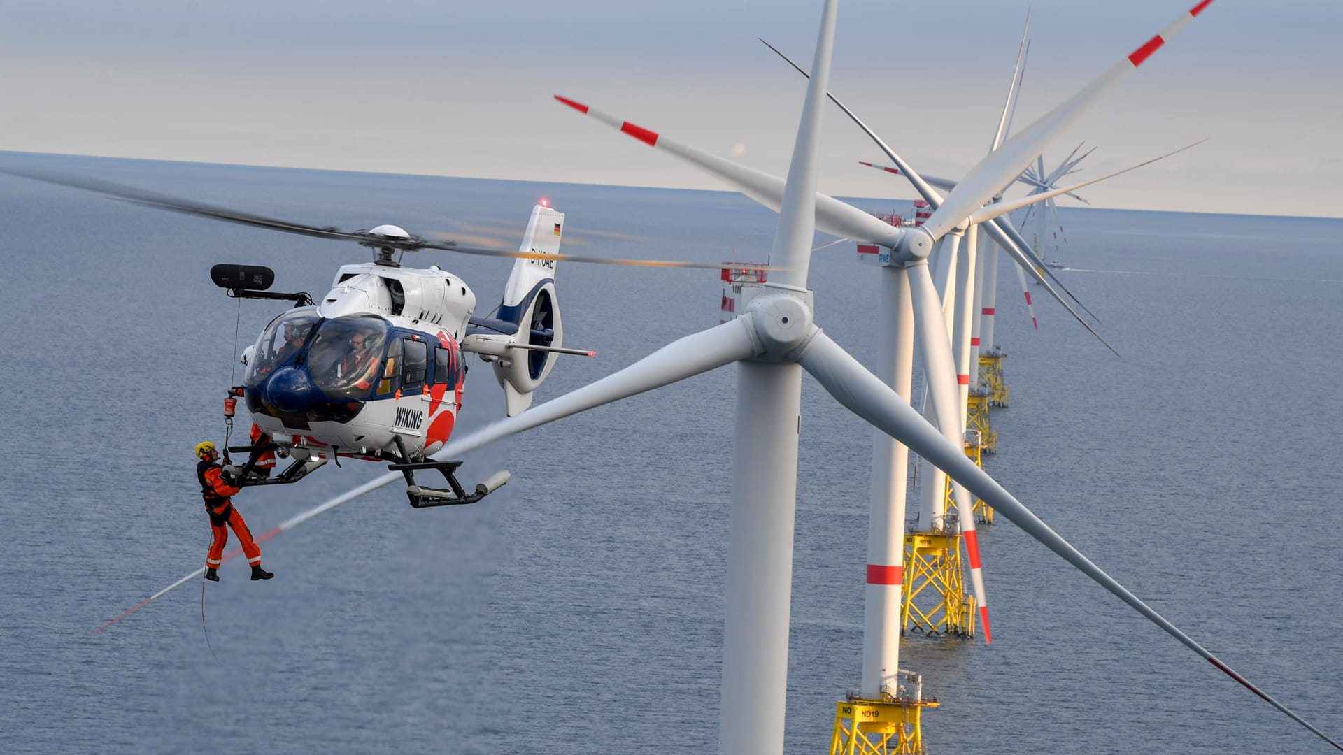 a windmill technician hanging from a helicopter