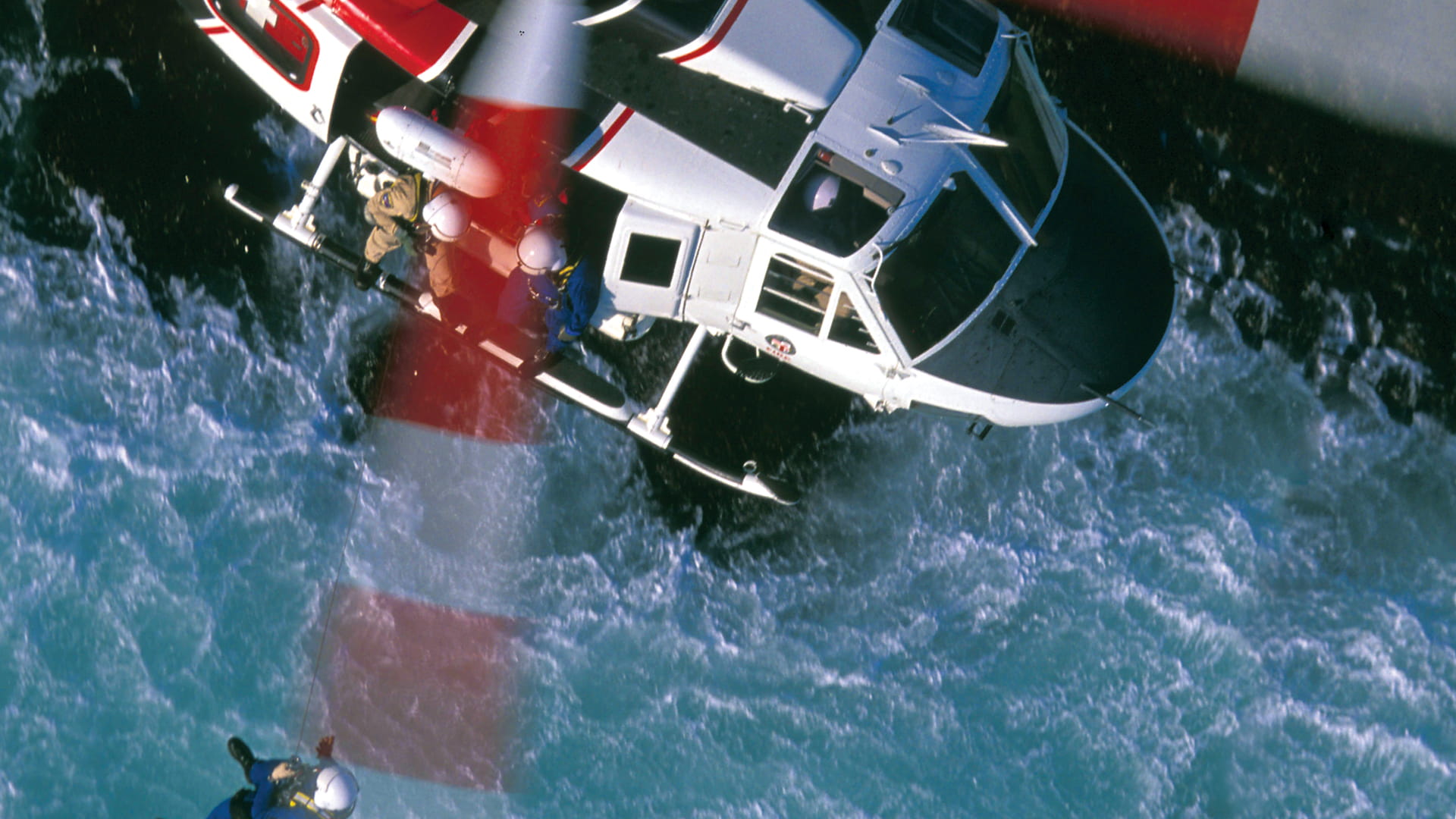 an overview shot of a helicopter rescuing a person from the ocean