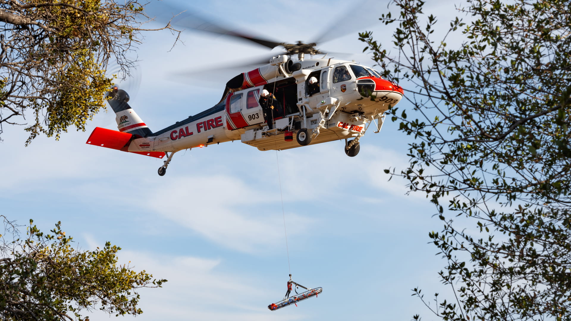 a helicopter hovering with a rescue hoist