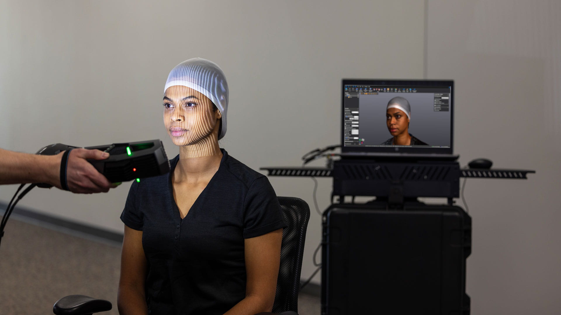 Technician using the Mobile Scanning Service (MSS™) scanner to scan woman's head for helmet fit