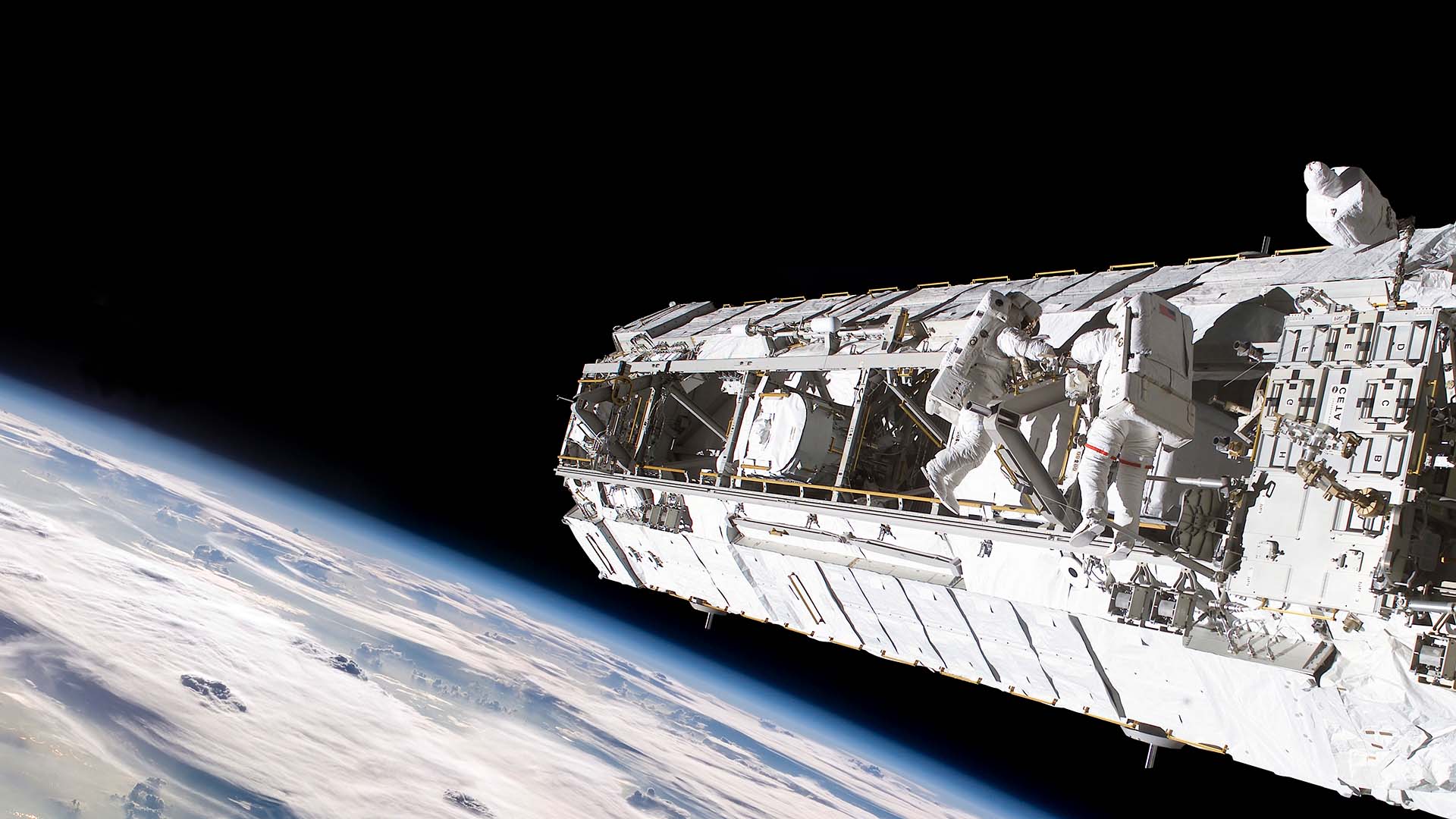 Astronauts in space suits on the exterior of a space station