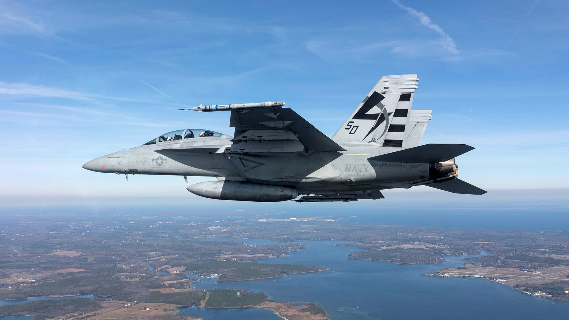 Aerial photo of U.S. Navy fighter jet with Tactical Combat Training System (TCTS) II attached to wing