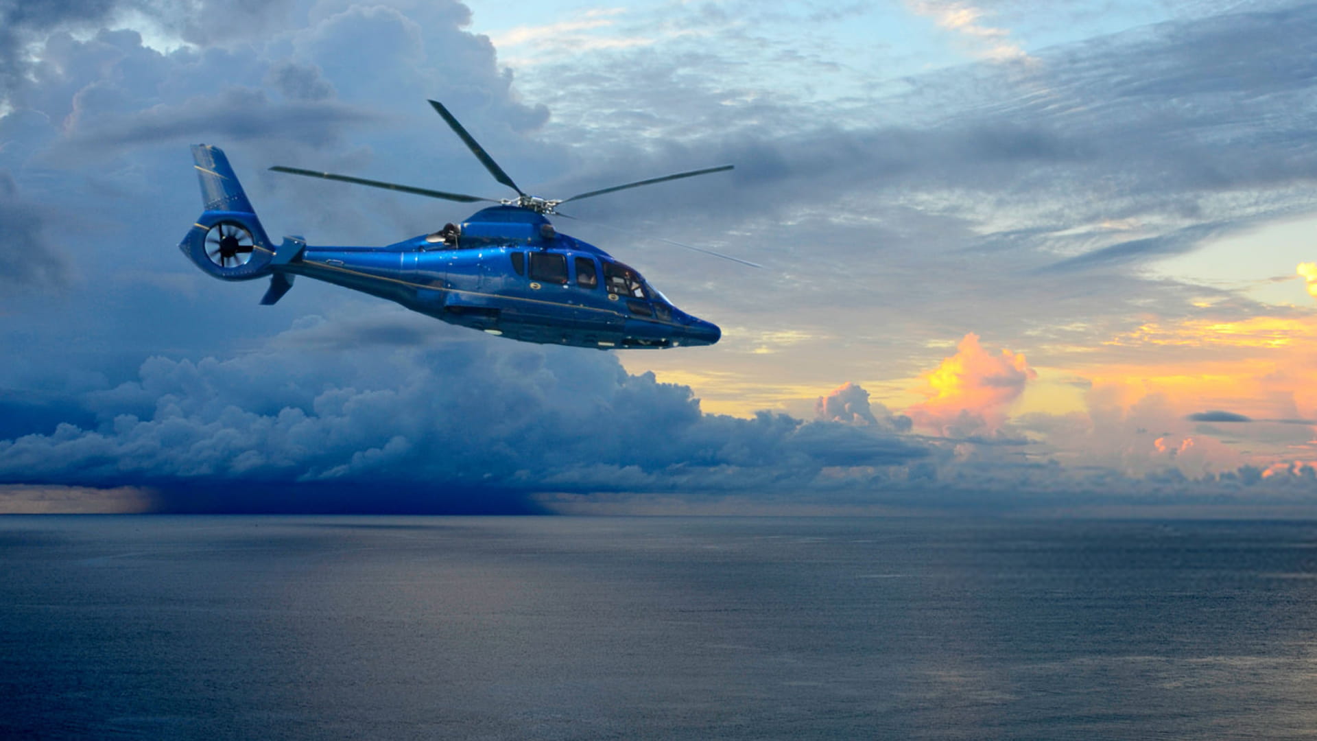 helicopter flying above ocean with dark blue clouds in the background