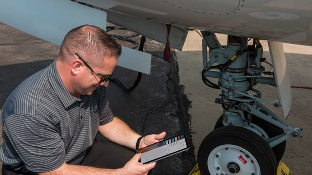 a technician holding a tablet inspecting landing legs