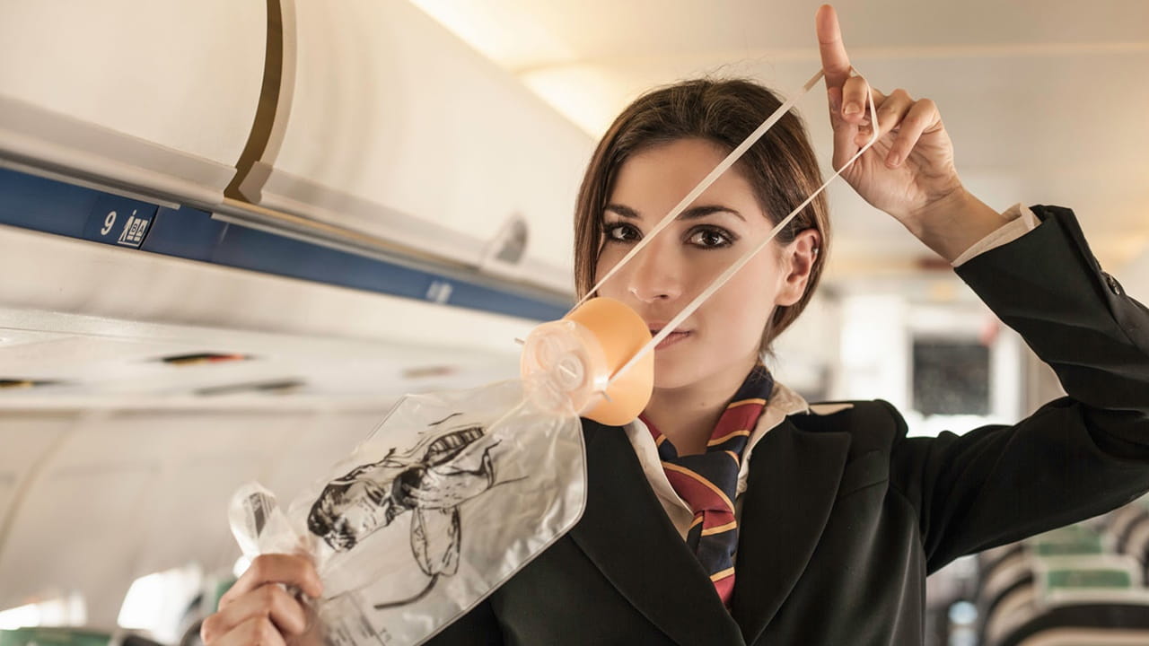 flight attendant demonstrating how to use oxygen mask 