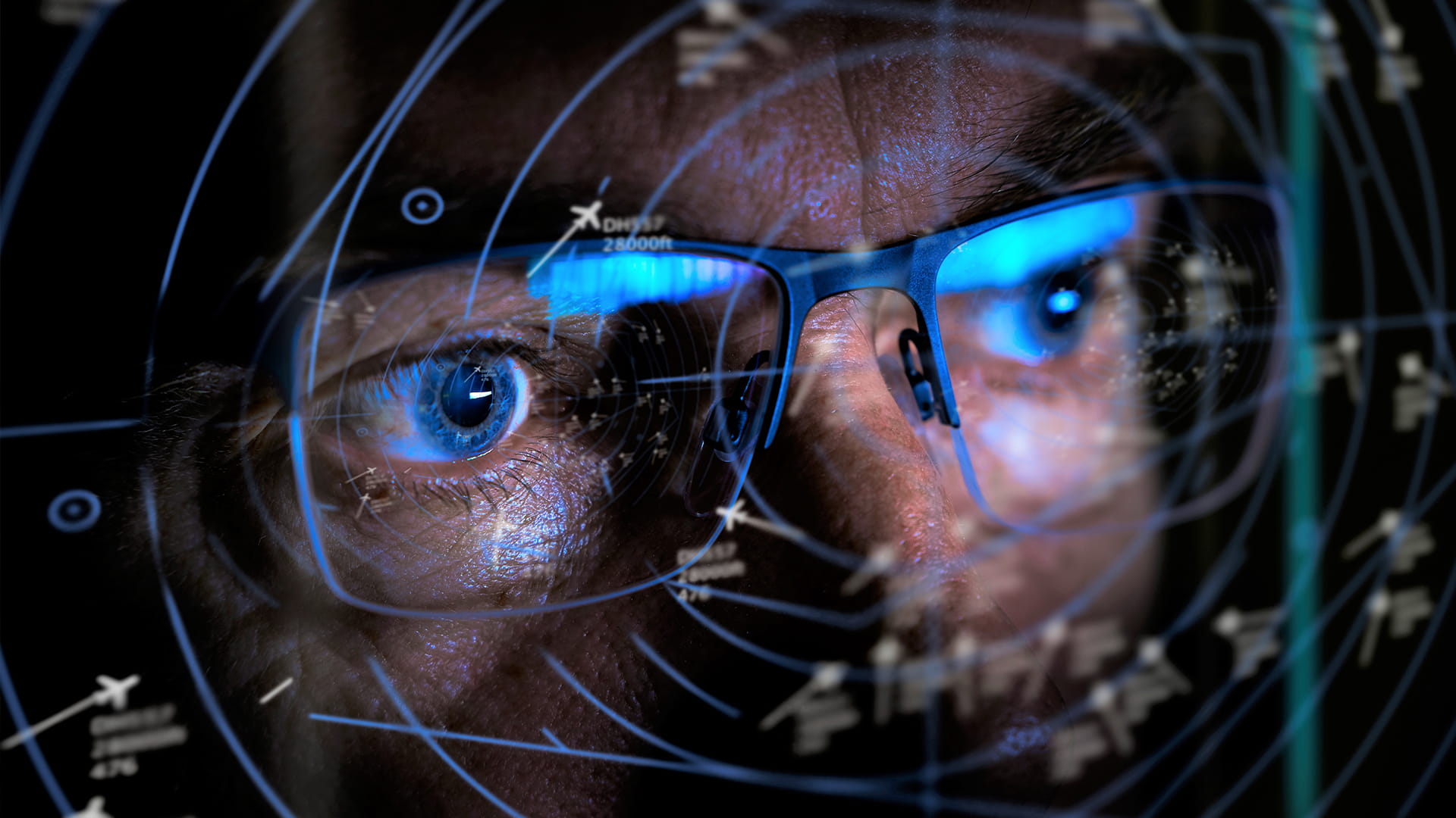 Close-up of a man wearing glasses looking at an air traffic control screen