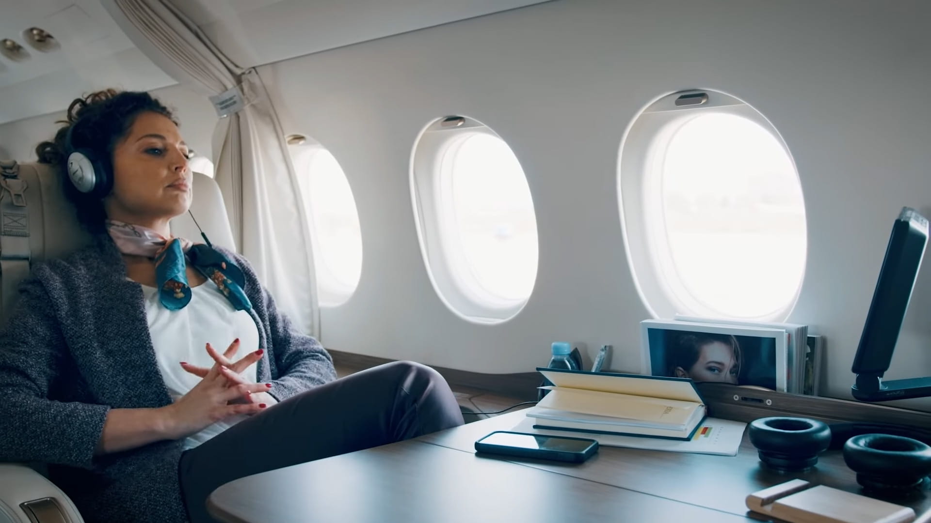 A woman relaxes in a business jet cabin while wearing headphones