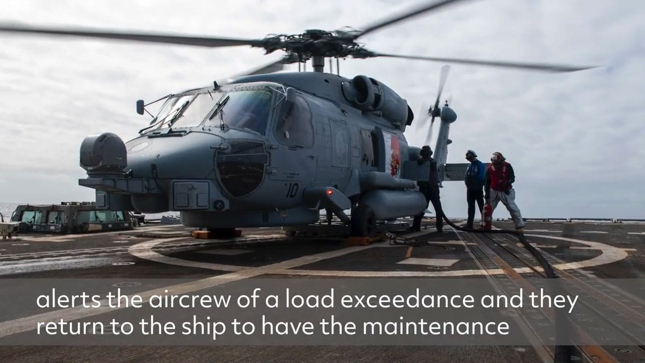 Maintenance crew working on a helicopter on the deck of an aircraft carrier