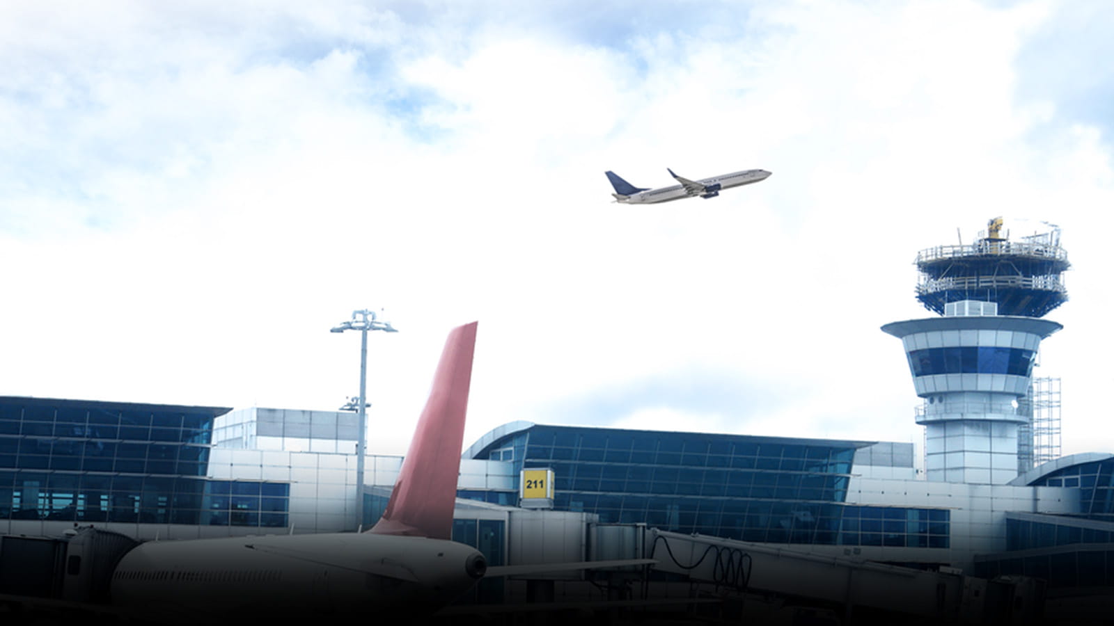 An airplane flies over an aircraft control tower