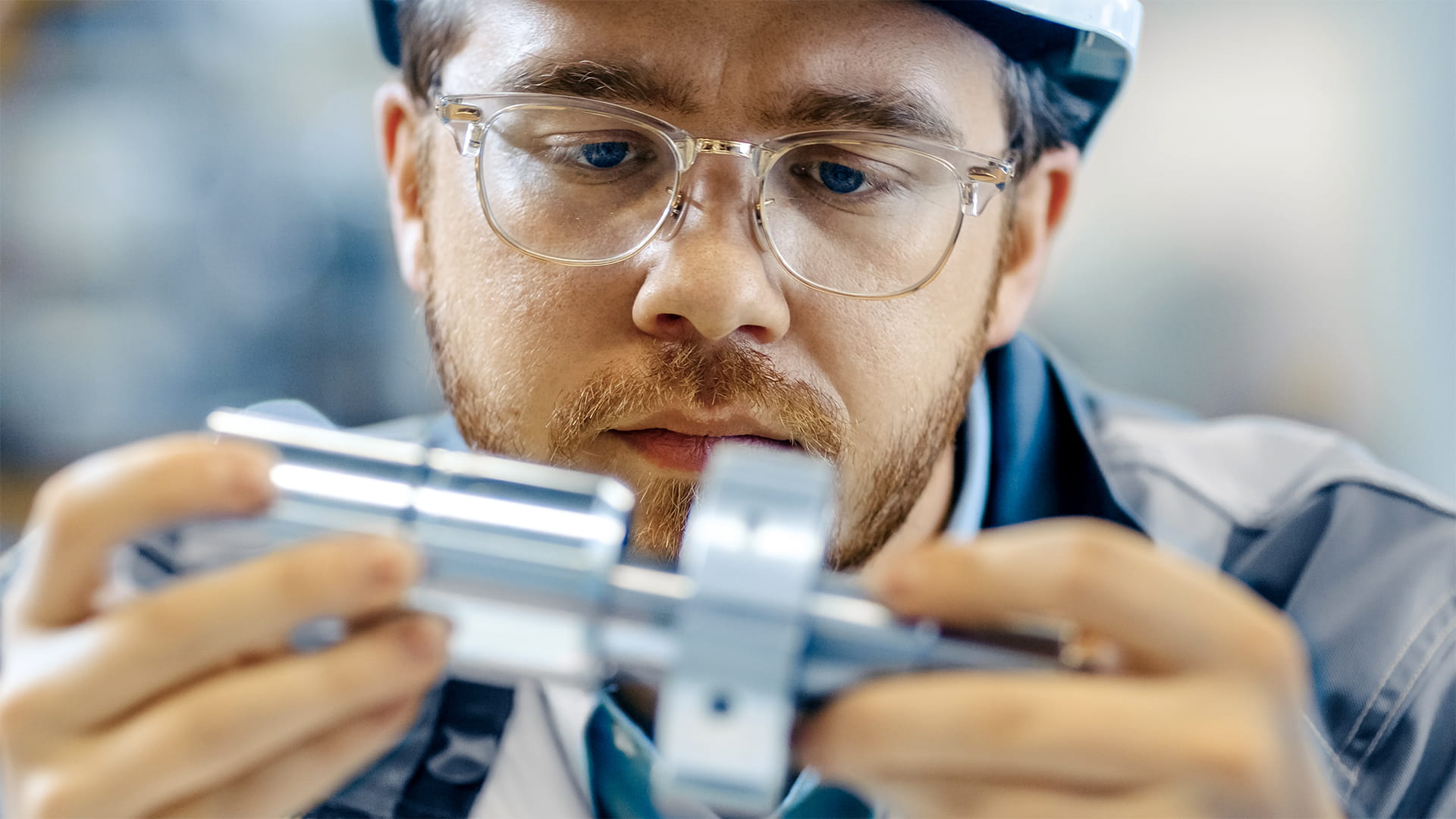 Close-up shot of an industrial engineer wearing glasses and hard hat connecting two components.