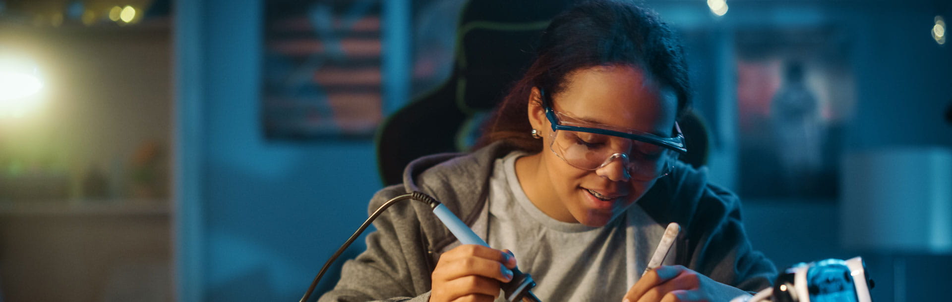 Young Teenage Multiethnic Schoolgirl is Studying Electronics and Soldering Wires and Circuit Boards in Her Science Hobby Robotics Project. Girl is Working on a Robot in Her Room. Education Concept.