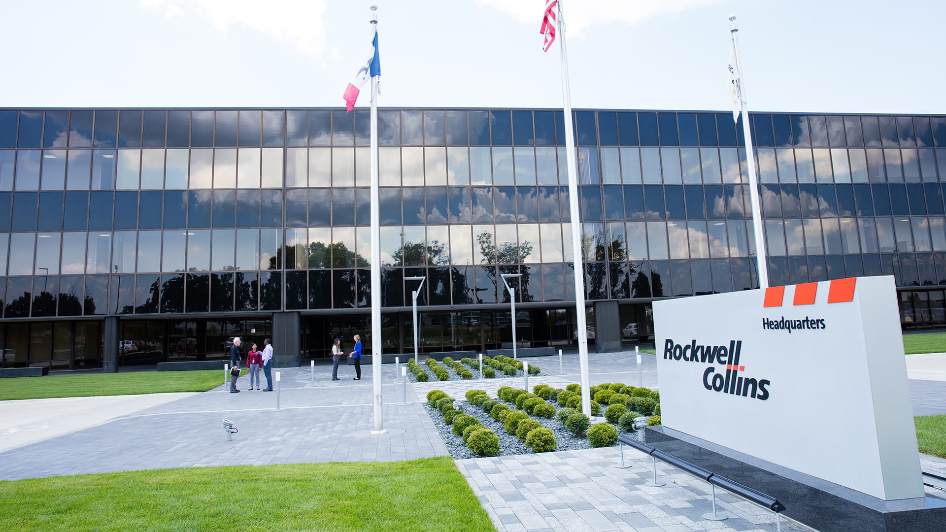 An office building with a monument sign and three flag poles