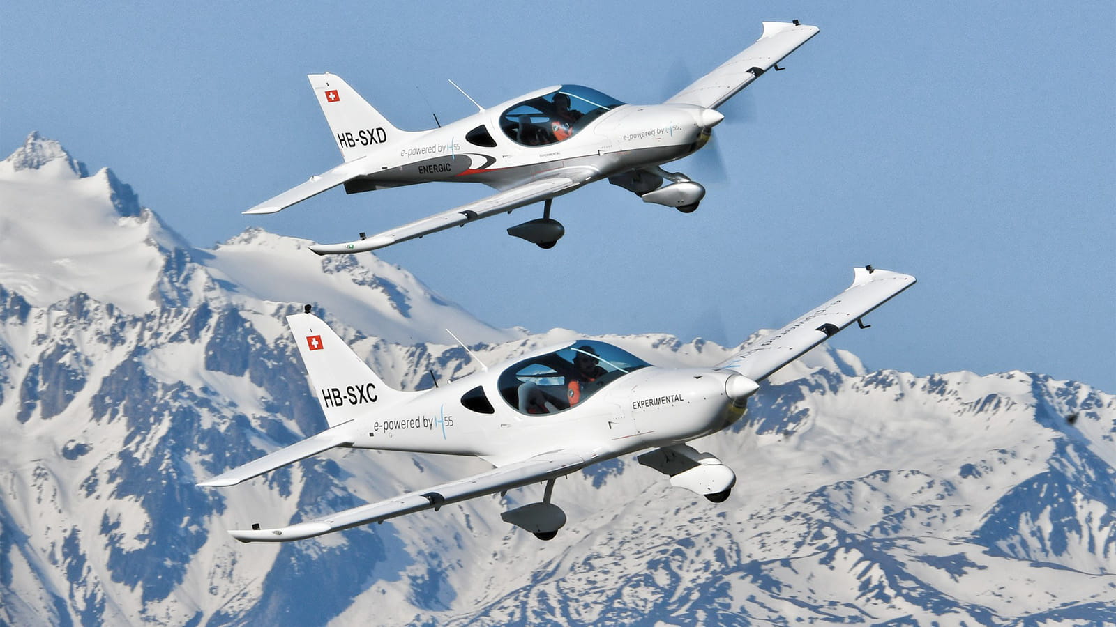 Two small aircraft flying over mountains