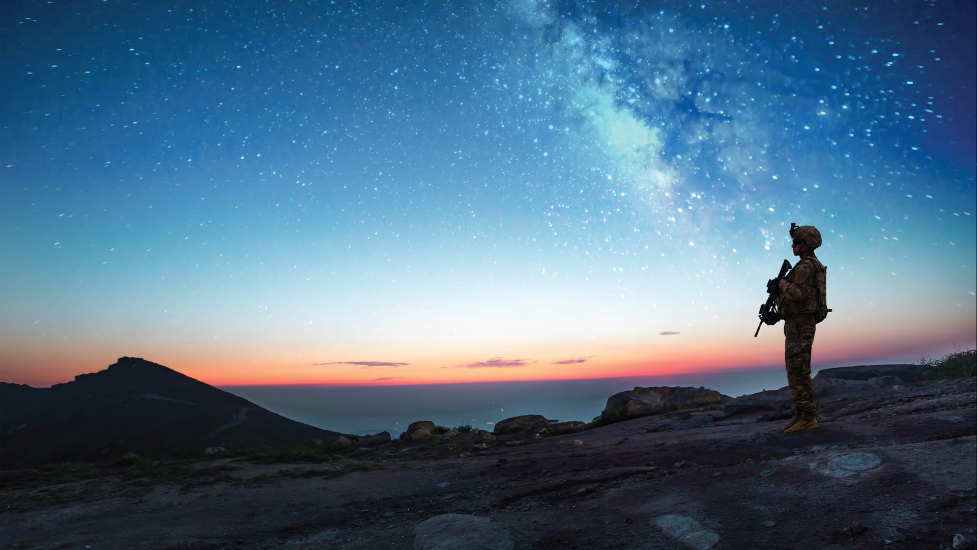 A soldier overlooks a city on a starry night