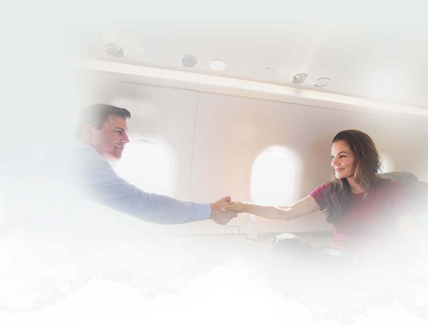 A man and woman shaking hands on an airplane