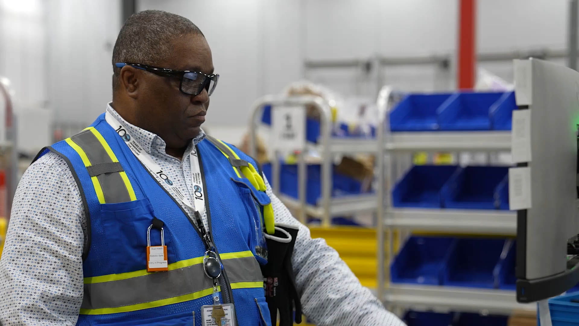 Robotics operator standing in front of screen in warehouse