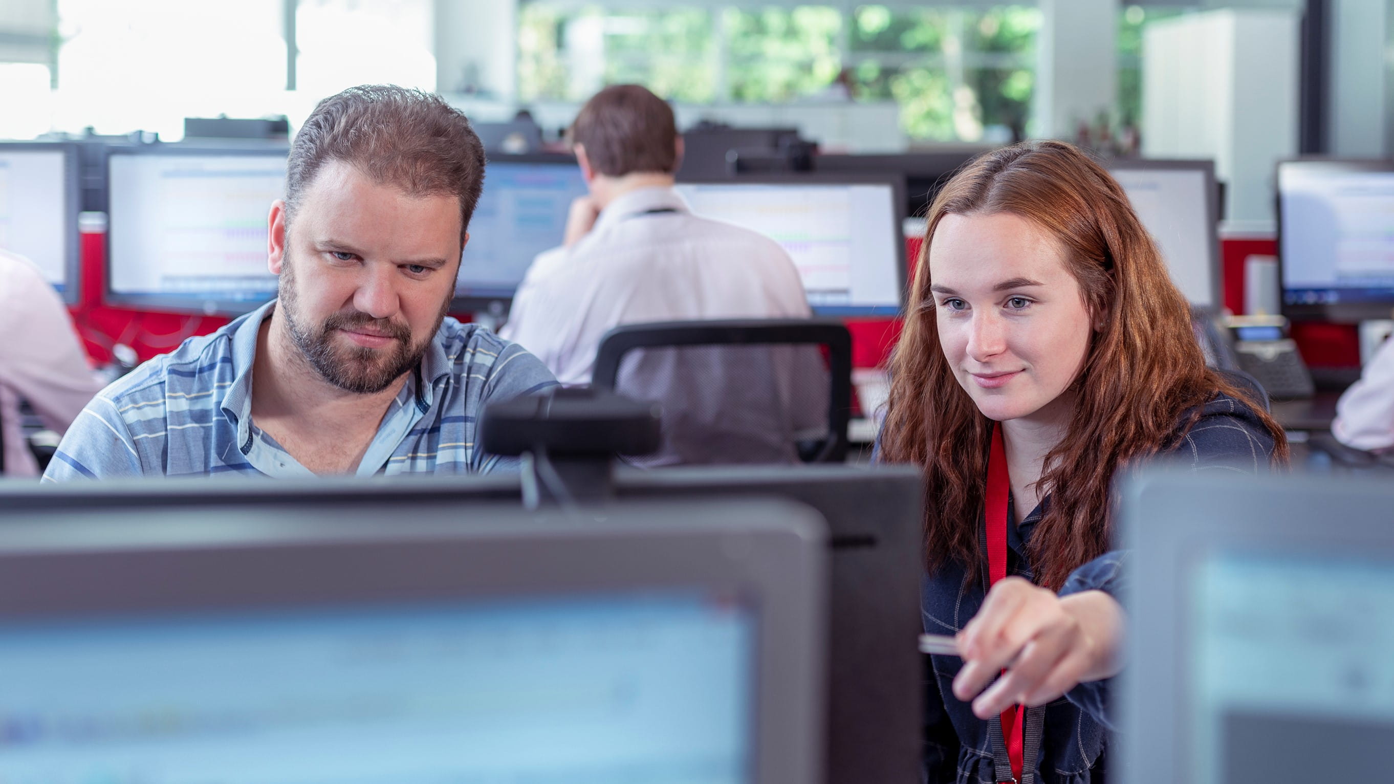 two office employees looking at computer monitors