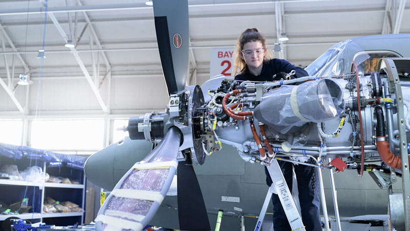 A technician working on a propeller plane