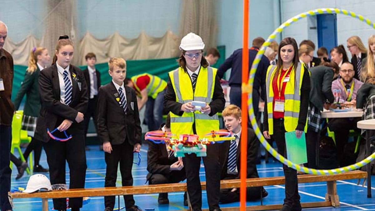 a group of kids and employees wearing a hard hat and a reflective vest