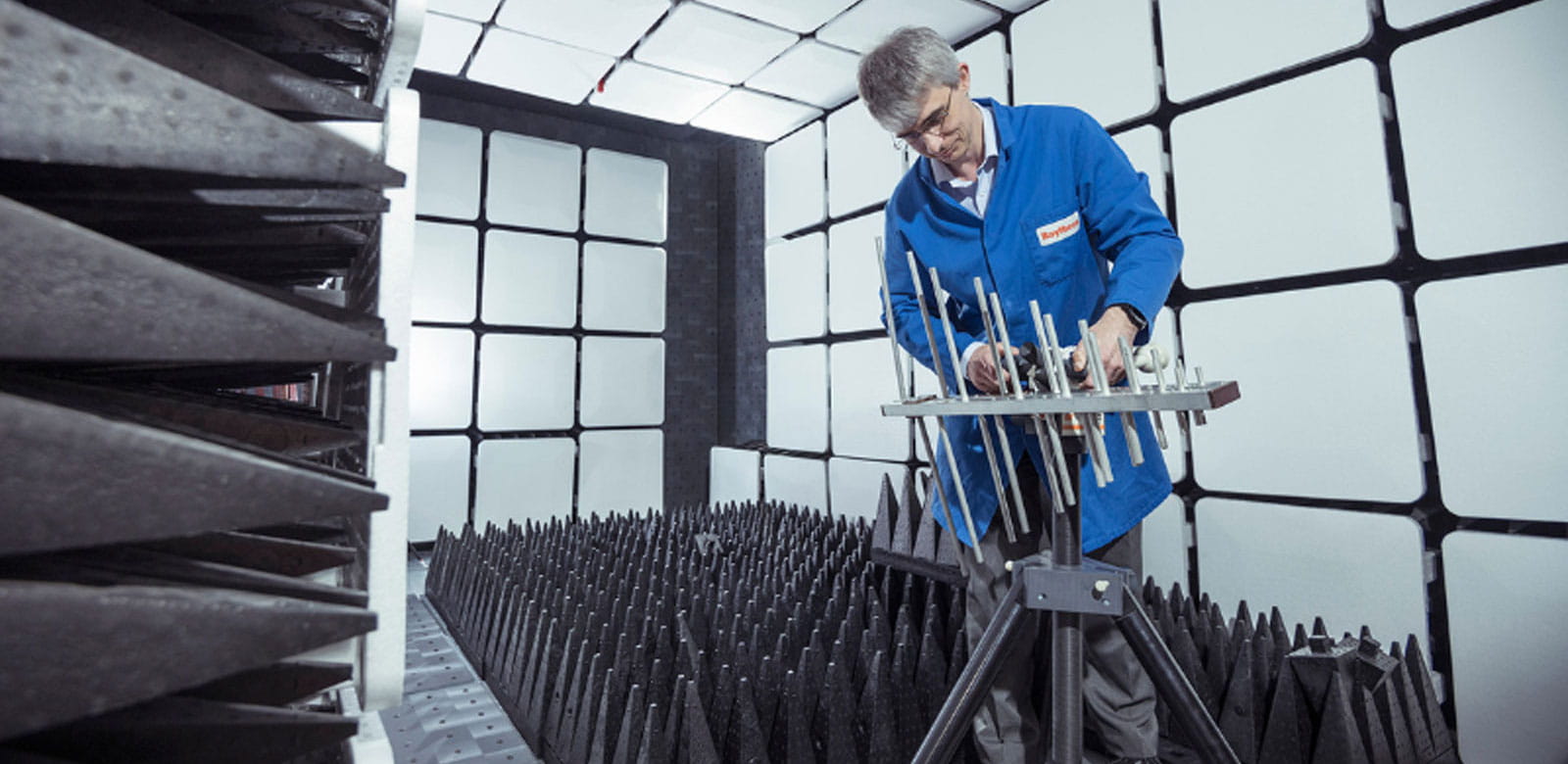 a technician in a blue lab coat inspecting defense materials