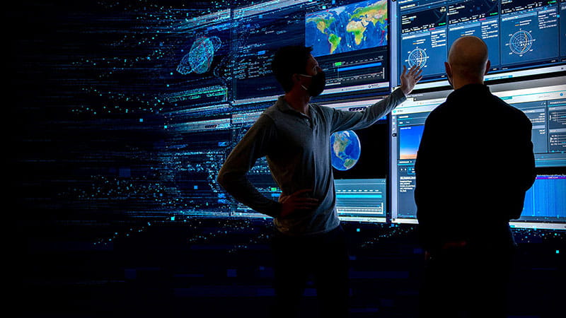 two corporate employees standing in a control towers analyzing satellite information