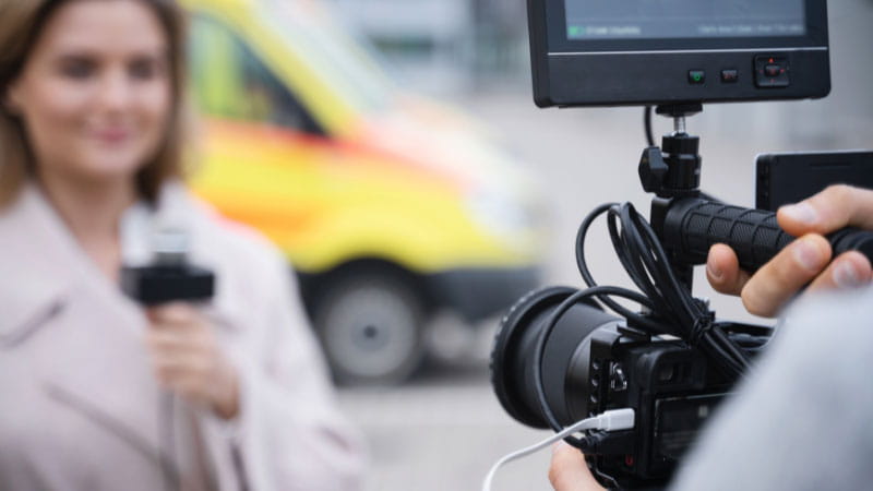 a female beat journalist standing in front of a camera