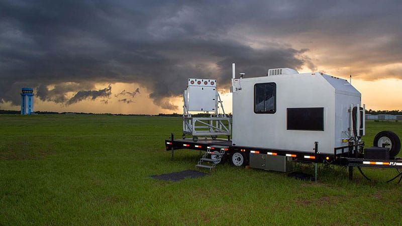 a picture of a trailer with a control center in a green field with a storm on the horizon