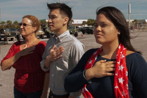 Donna Boerner, Justin Yang and Alexandra Cintron-Aponte hold their hands over their hearts during a Veterans Day ceremony at Raytheon's facilities in Largo, Florida.