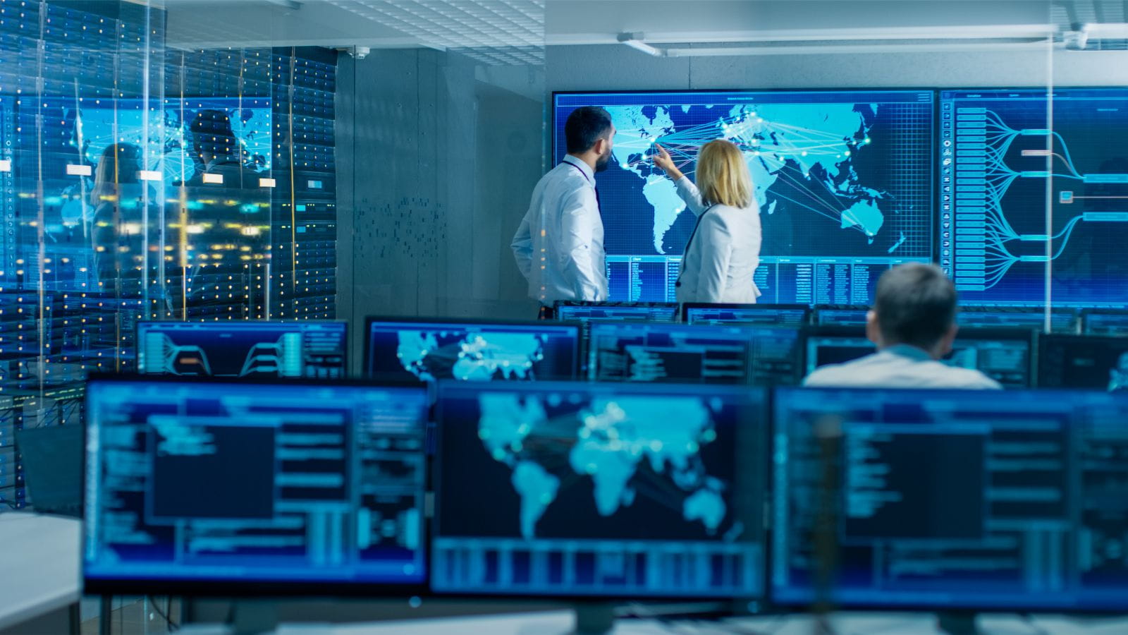 Colleagues discuss technical data on screens in operation centre