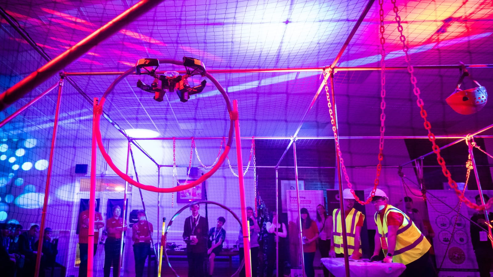 Pupils and STEM ambassadors watch a quadcopter fly through a hoop