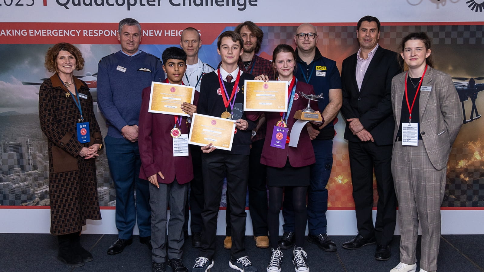 The winning team gather on stage with their certificates and trophy