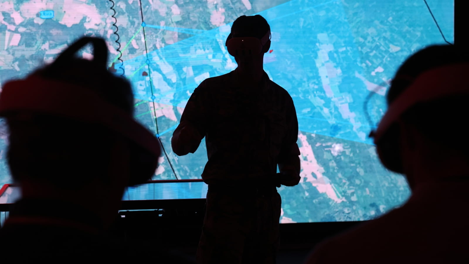 A silhouette of soldiers standing in front of a digital screen