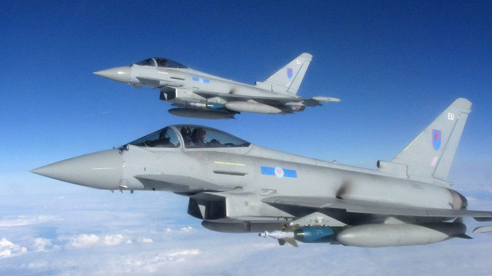 Two RAF Typhoons fly over clouds with blue sky in the background