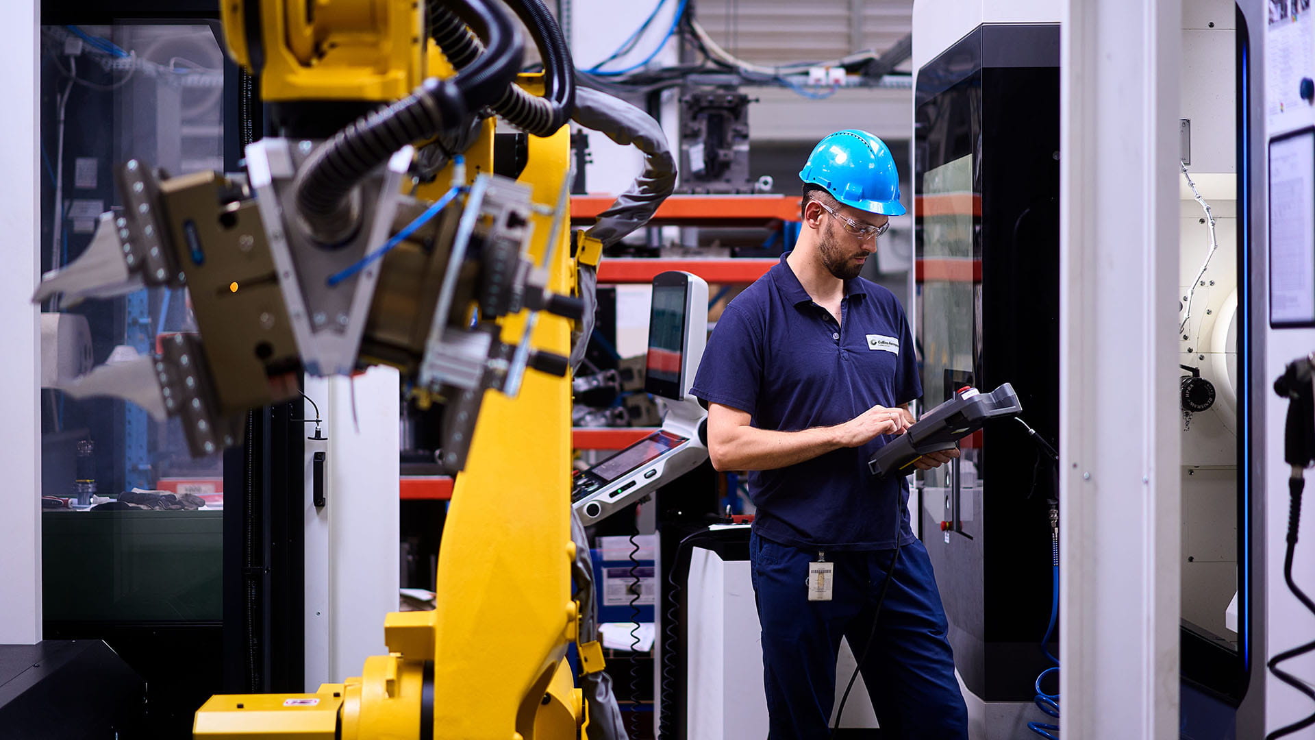worker next to robot in Collins Poland manufacturing facility