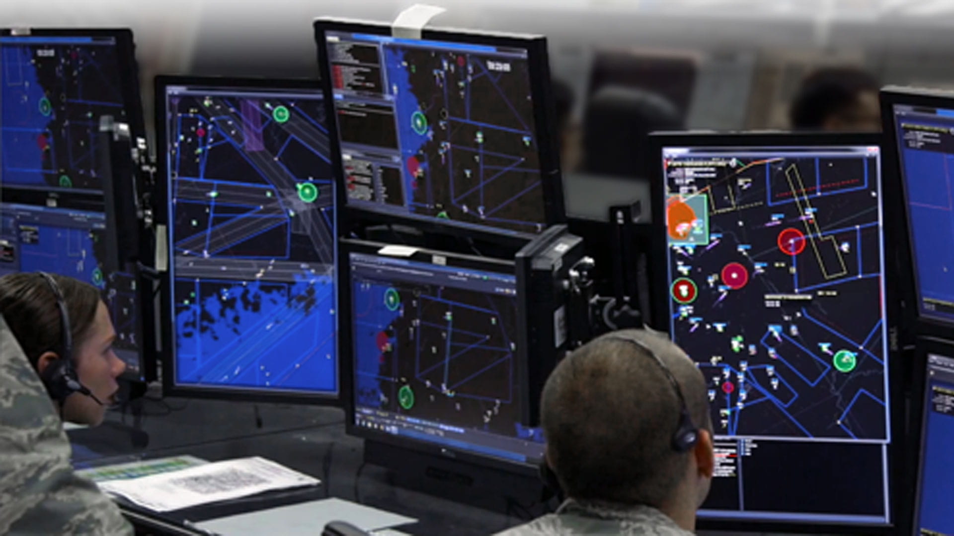 Operators viewing multiple monitors in a military command center