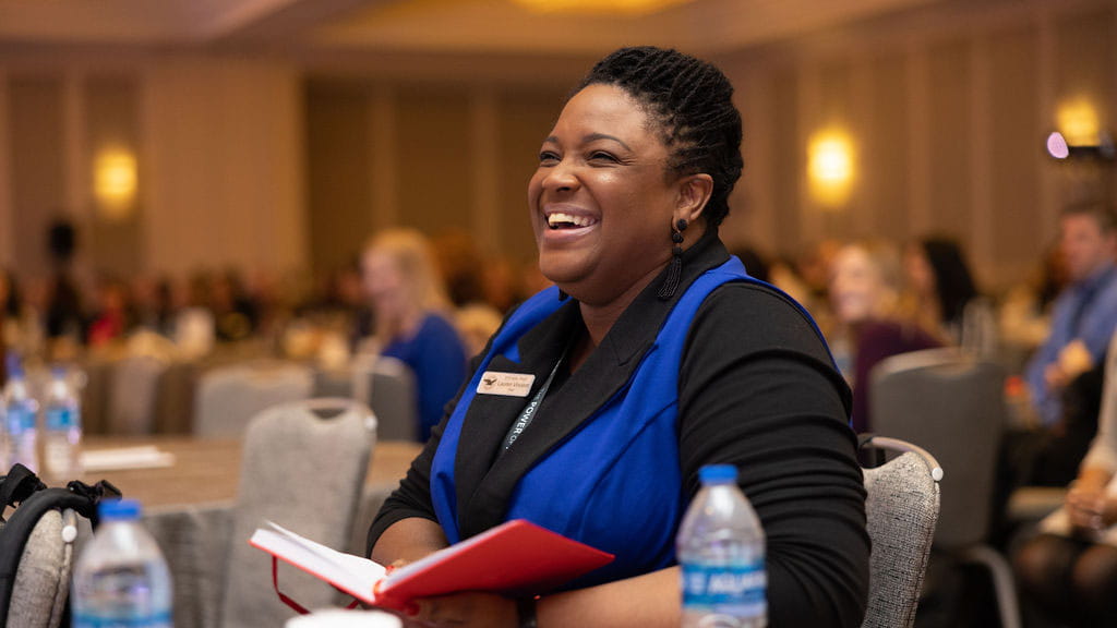 Woman smiling holding a note pad in a conference room