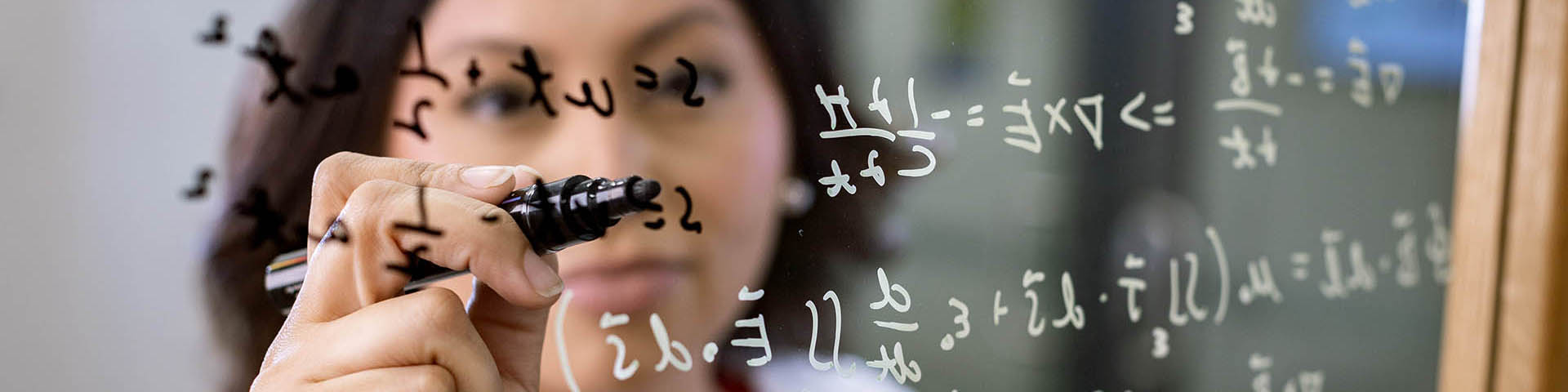 a woman writing formulas on a transparent board