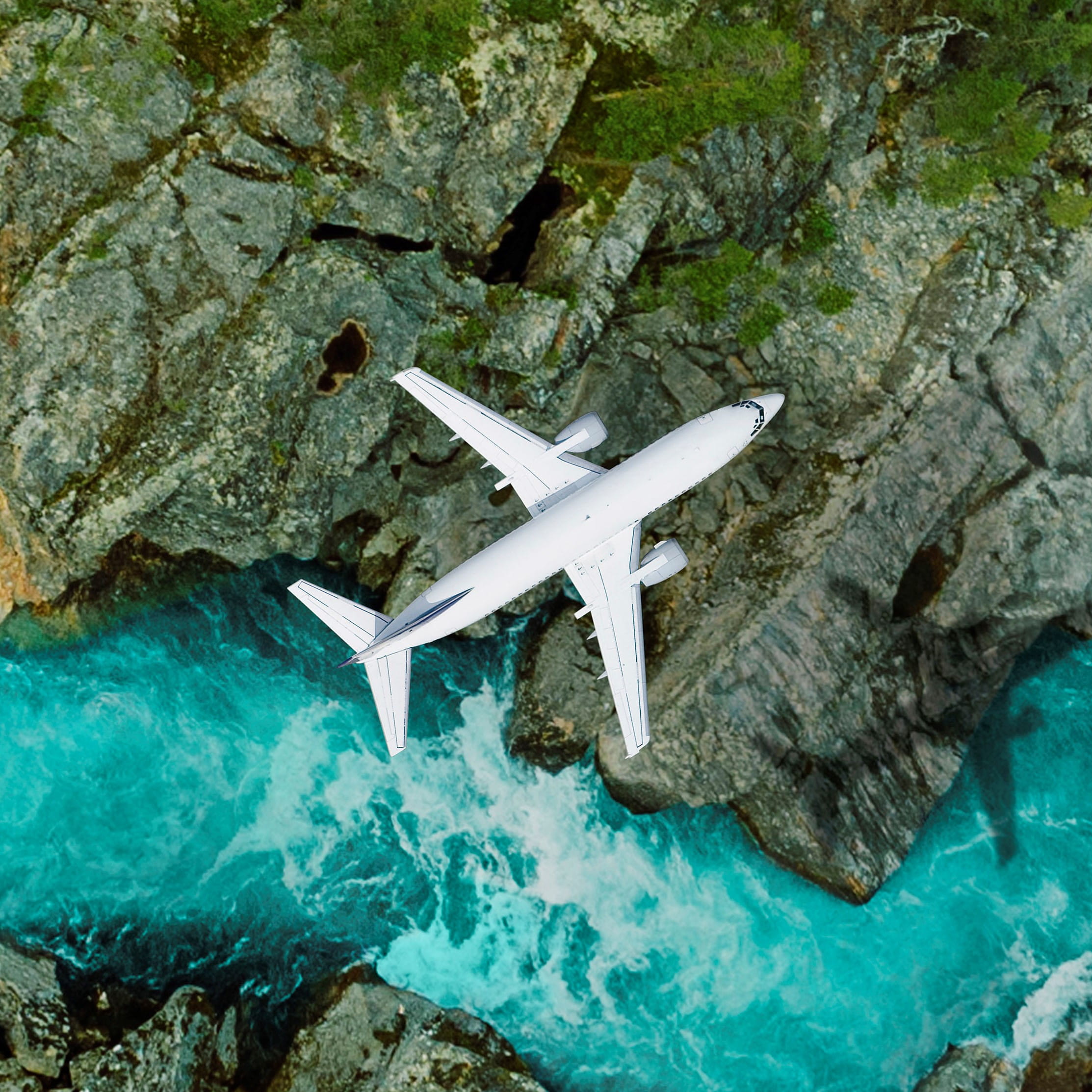 a photo of a commercial airplane flying over a blue river and rocky landscape