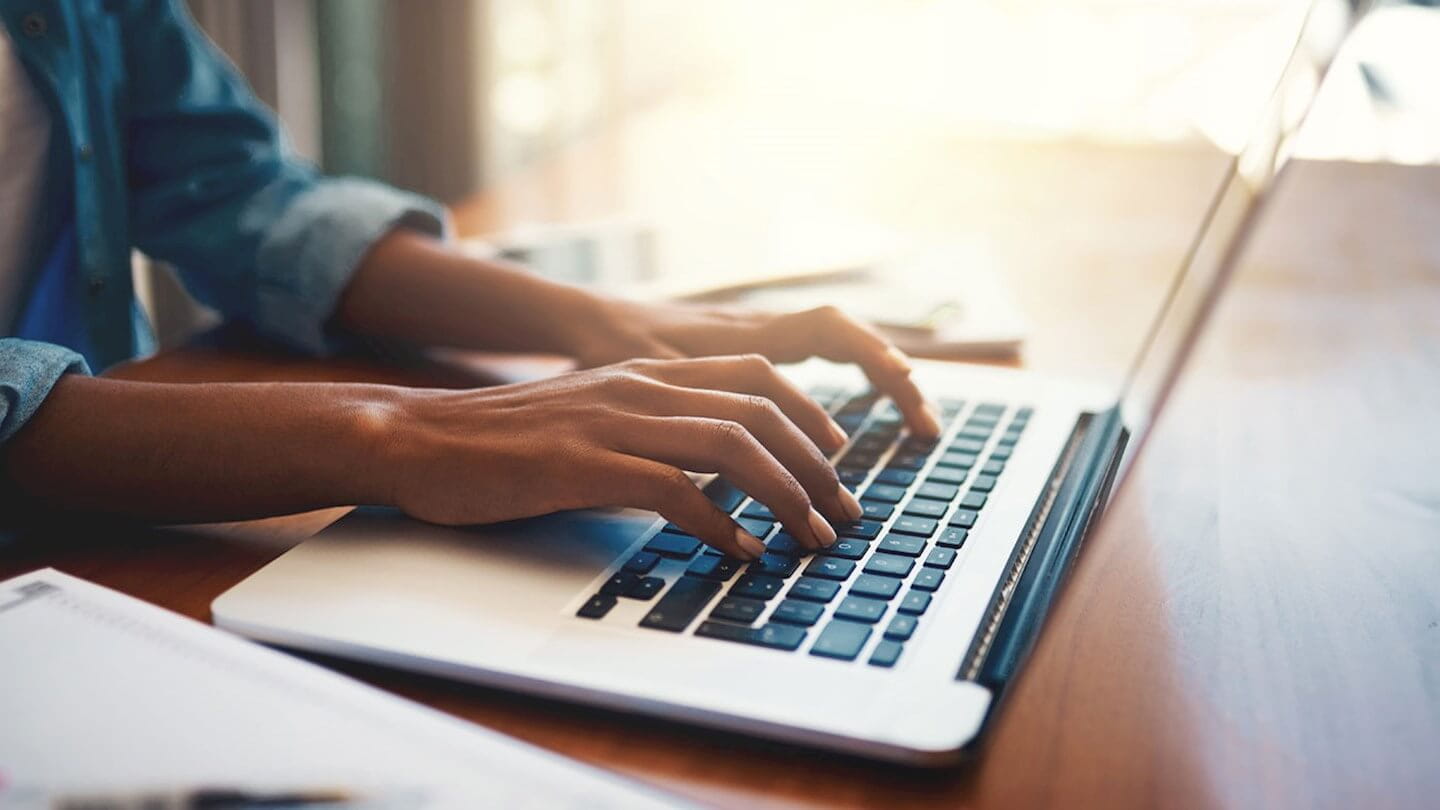 Close-up of a woman's hands typing on a laptop