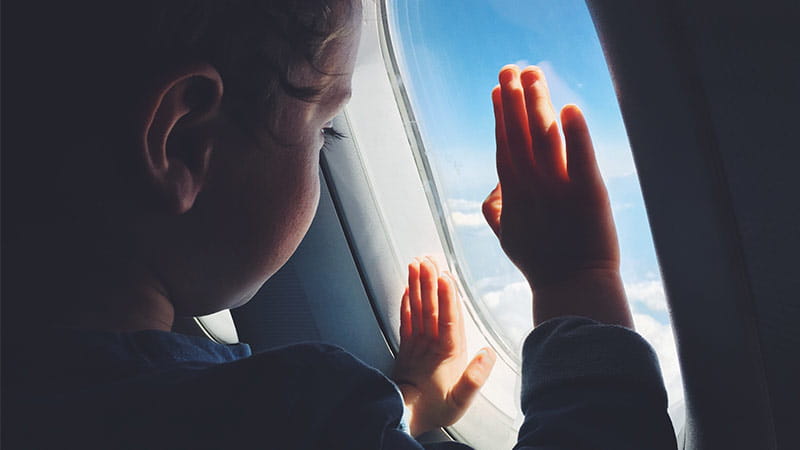 Kid looking through plane window