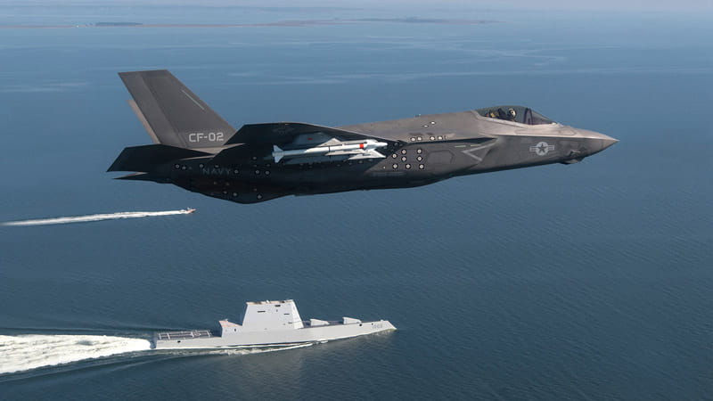 Fighter jet flying over a frigate