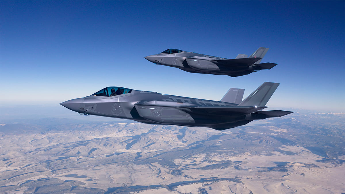 Two jet planes flying over terrain