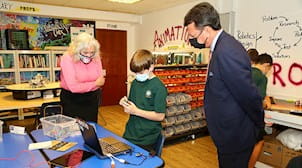 Two adults watching a child working with STEM project