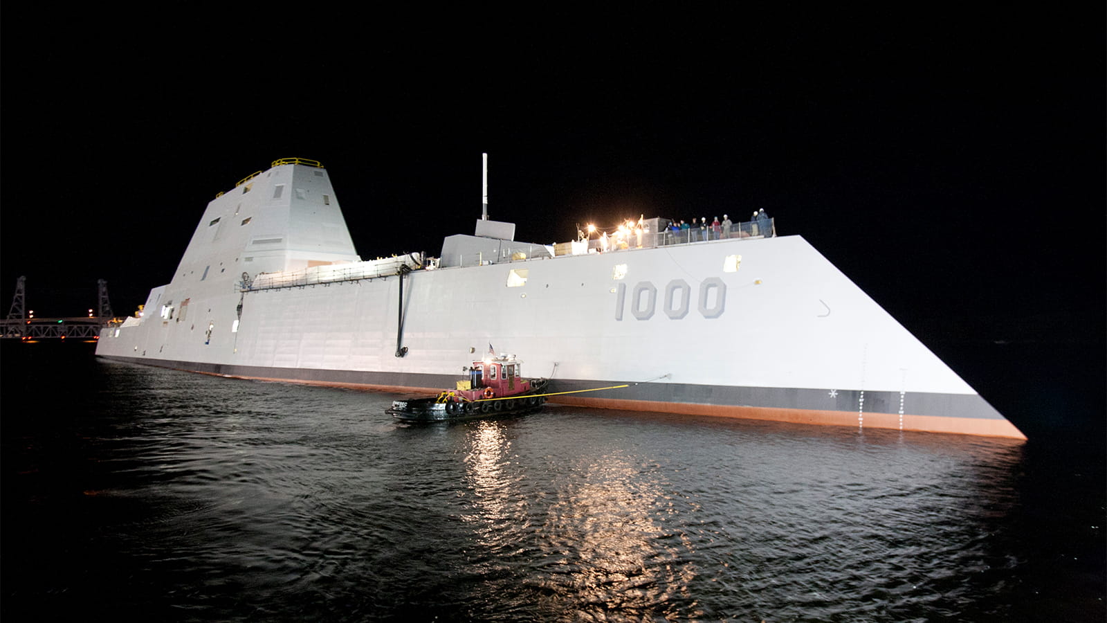 A U.S. Navy Zumwalt-class destroyer on the water at night.