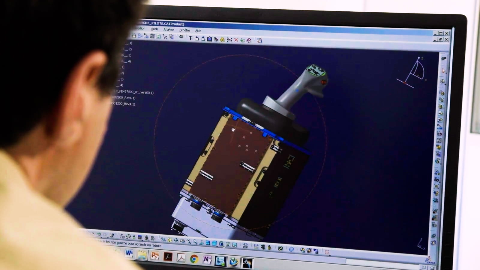 A man looks at a computer screen showing a 3D model of a part.