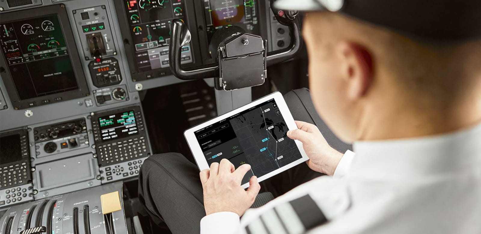 a pilot in the cockpit looking at the flight route on a tablet